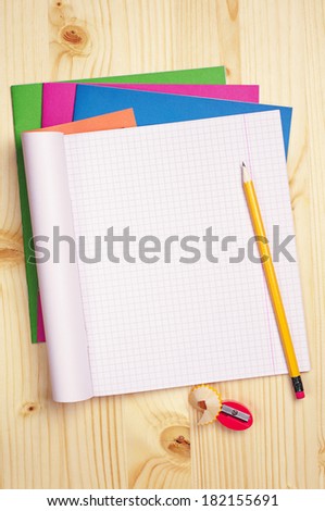 Opened exercise books and pencil on wooden table