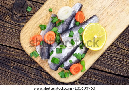 Marinated fish on a cutting board on table. Top view