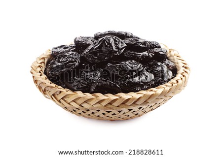 Dried plum in wicker bowl on white background