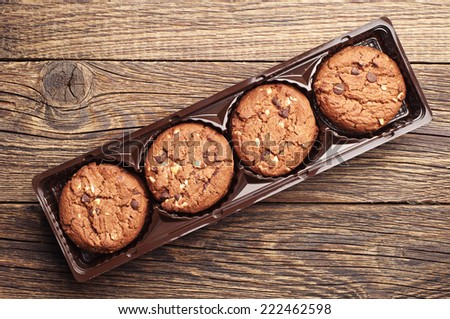 Chocolate cookies with nuts in packing on wooden background