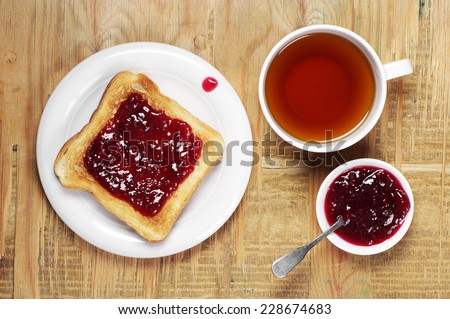Toast with jam and cup of tea on old wooden table. Top view