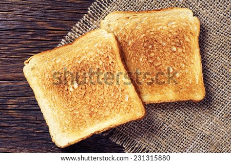 Two toast bread on wooden background closeup. Top view