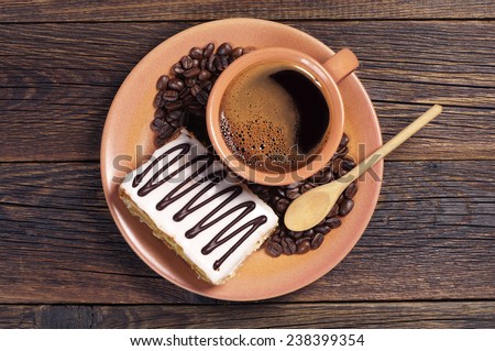 Plate with cup of hot coffee and creamy cake on dark wooden table, top view