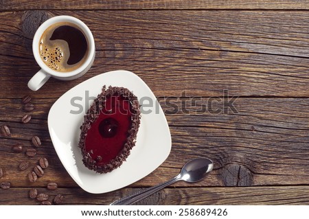 Coffee cup and cake with cherry jelly on dark wooden table, top view