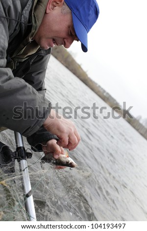 The fisherman is removing fish from the net on the river