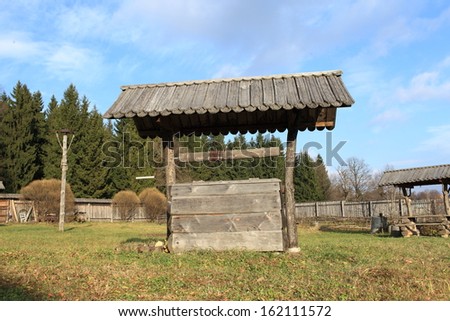 Old outdoor wooden wishing well with pine roof