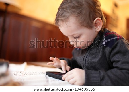 Boy playing on the smartphone in the restaurant