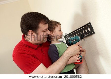Father and his son installing mount TV on the wall at home