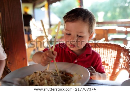 The boy eating noodles in an asian restaurant