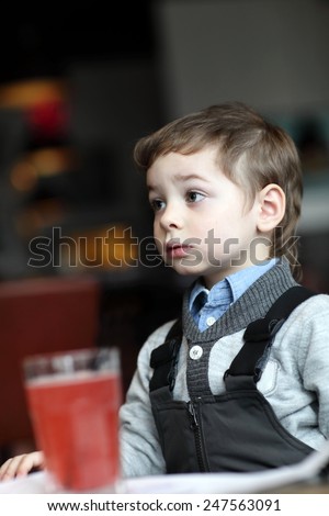 Portrail of thinking child with red juice in the cafe