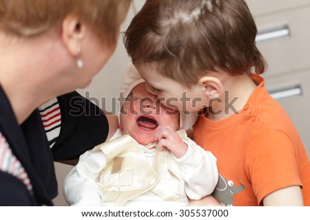 Newborn crying on his grandmother hand at home