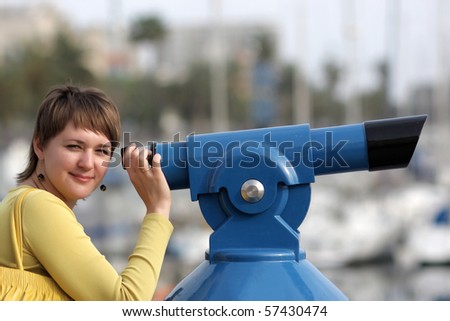 The woman poses with telescope at summer