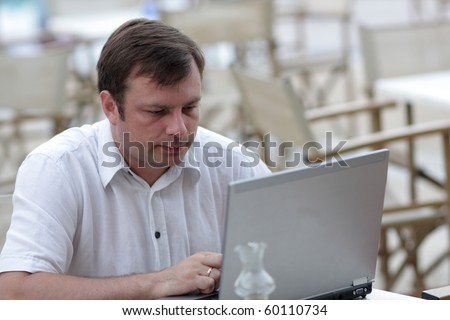 The man is sending mail by laptop at the cafe