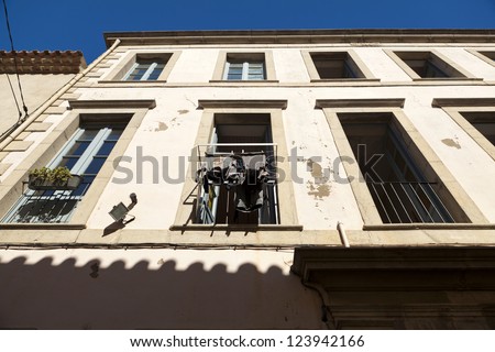 View of a house facade with windows and a drying rack in front of a window in south france