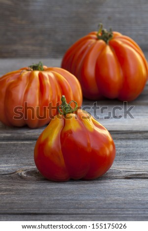 Three large Beefsteak Tomatoes fresh from the Weekly Market on a old wooden Table