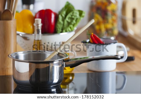 Cooking Pot with Wooden Spoon on Ceramic Hob with Copy Space in the upper and right Area of the Image