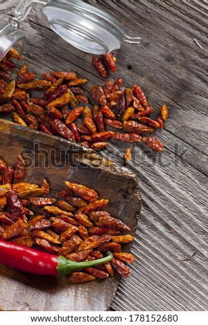 Fresh and dried chili peppers on an old wooden scoop and a Storage Jar with copy space on the right side of the image