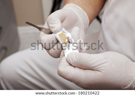 Chiropodists unpacks a scalpel blade from the packaging