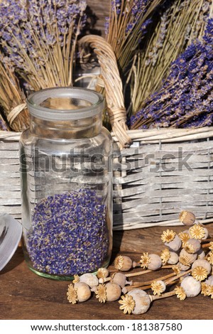 Storage jar dried lavender blossoms and poppy capsules on a table in front of a garden shed