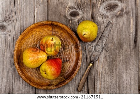 Pears on a wooden plate with a knife on an old rustic wooden table in country style
