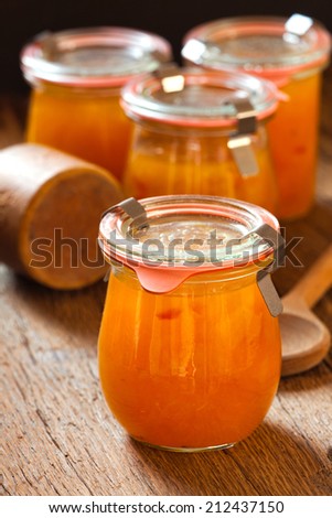 Homemade melon jam in a preserving jar on rustic wooden background in country style