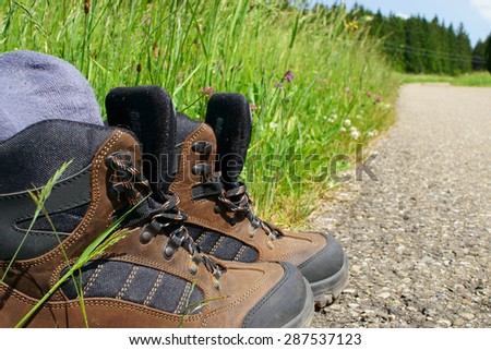 Close-up of Hiking boots with stockings on the roadside beside a summer meadow