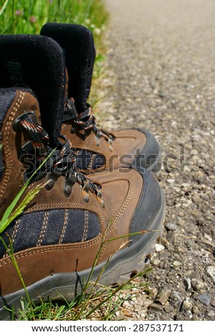 Close-up of Hiking boots on the roadside beside a summer meadow