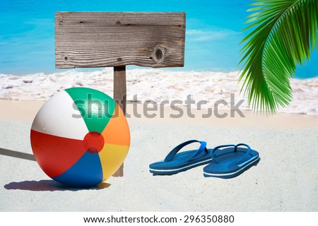 Colorful Beach Ball, Flip Flops and a wooden Signboard on the Beach