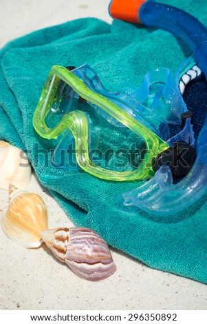 Diving equipment, Diving goggles, snorkel, towel and seashells on the beach