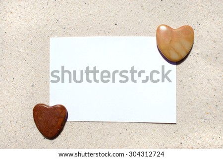 White blank postcard with hearts of stone on the beach
