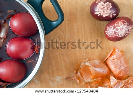 Traditional coloration eggs with slate or onion skin. Pot, easter eggs, onion skin at wooden background.