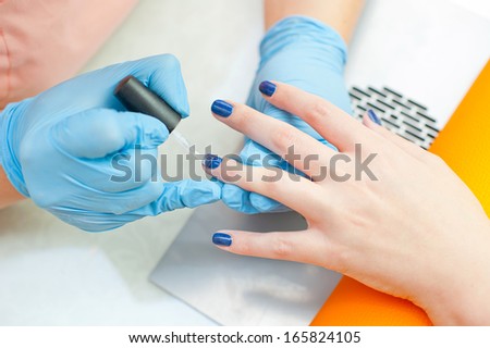Beautician making manicure in spa or beauty salon - painting fingernails.