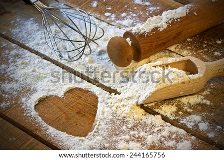 flour, rolling pin and heart with wood background