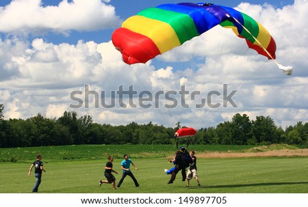 WATERDOWN, ONTARIO/CANADA - AUGUST 2013: Skydivers in tandem jump just before land with security team around on August 4, 2013 in Waterdown. Parachutist and first time jumper on Civic holiday
