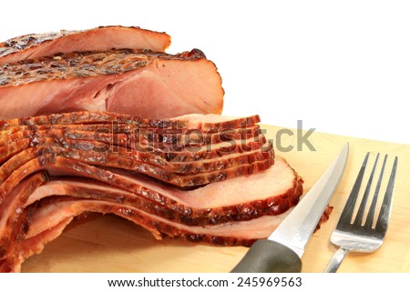 Close-up view Finally backed pre cooked smoked Spiral-cut of Pork Ham over wooden cutting board ready to arrange American South Traditional New Years Day meal over white background
