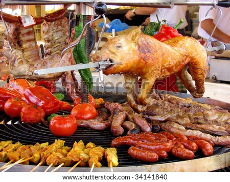 pig, meat and vegetables in course of barbecue preparation at spring fair in Barcelona, Spain