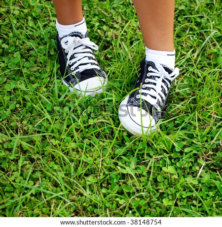 feet of the child  in gym shoes on a grass