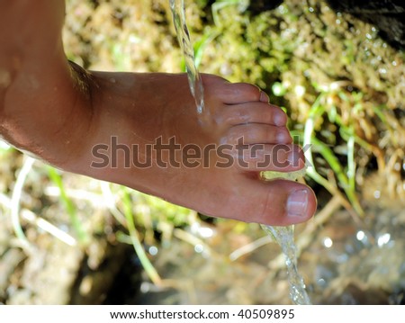 tired female feet in water of the mountain river