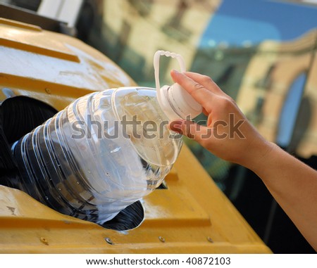 female hand throwing out a plastic large bottle in container for processing and recycling
