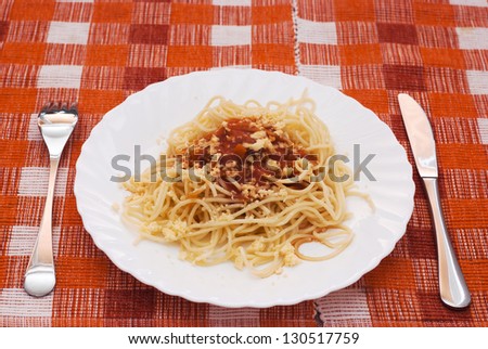 Italian spaghetti with sauce on the patterned tablecloth.