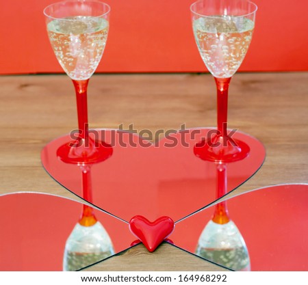 Mirroring of two champagne glasses and little red heart.