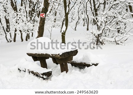 Snowy benches and red bike sign. Winter tourism.