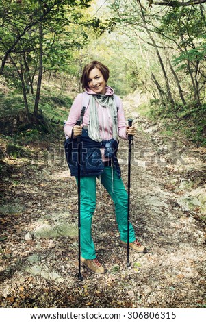 Young female traveler with hiking poles in autumn outdoors. Beauty and nature.