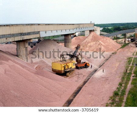 A Construction vehicle loading sand onto a cargo truck