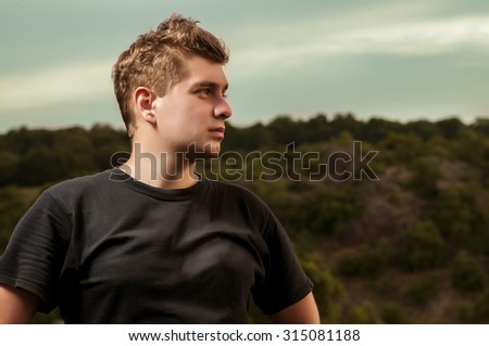 Young man standing outside  with the forest background