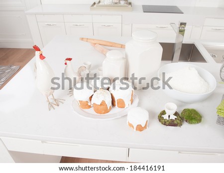 Cakes, flour and cock service are in the kitchen with white furniture in Easter eve