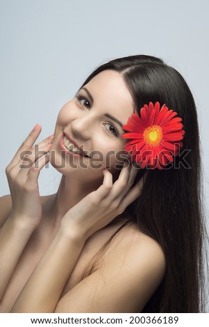 Portrait of happy young pretty woman with red daisy in her hair, dreaming about future. Isolated on the white background