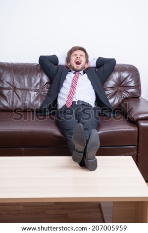 Very tired businessman having a rest in his office after hard working day and dreaming about warm soft bed at home