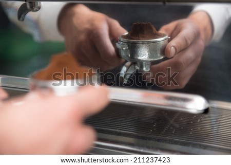 Selected focus on hands of professional barista holding ground coffee in special form of coffee machine