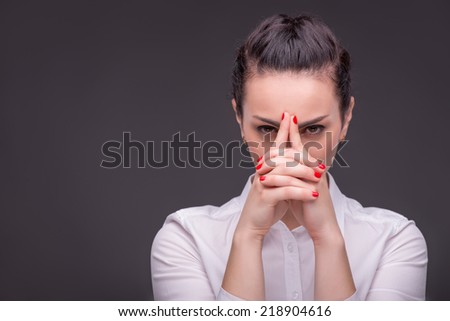 Half-length portrait of dark-haired beautiful woman wearing white blouse having a nice manicure thinking hard about something. Isolated on dark background